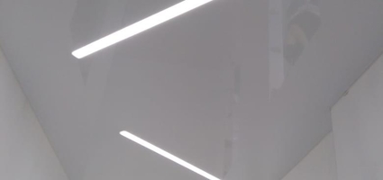 Белый-глянцевый натяжной потолок со световыми линиями в коридоре