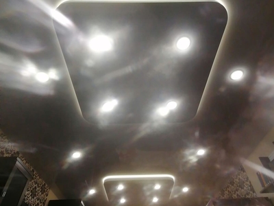 Двухуровневый двоевыпуклый натяжной потолок с подсветкой в спальной комнате 