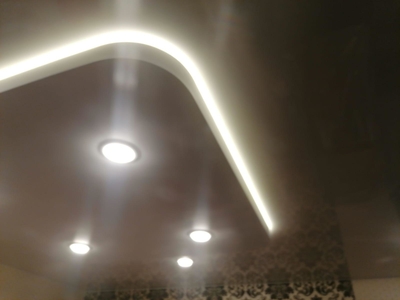 Двухуровневый двоевыпуклый натяжной потолок с подсветкой в спальной комнате 